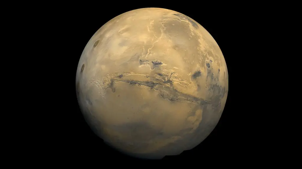  Mars is a reddish brown in this image from a spacecraft. A deep gash, the Valles Marineris canyon, is visible across the center of the planet.